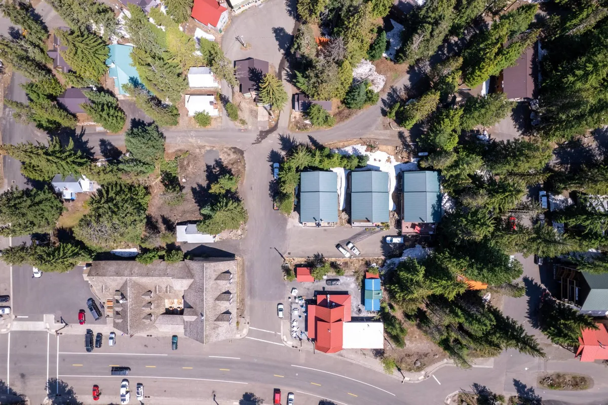 A serene overlook featuring clusters of trees, colorful rooftops of local buildings, and intersecting roads that suggest easy access to dining, shopping, and area attractions. The vibe is tranquil yet lively, highlighting the proximity to community hotspots and nature.