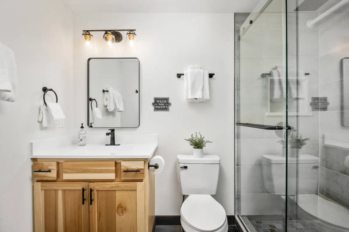 A modern bathroom with a vanity and sink, a large mirror, a shower area, and soft lighting, creating a serene spot for freshening up after the day’s adventures.