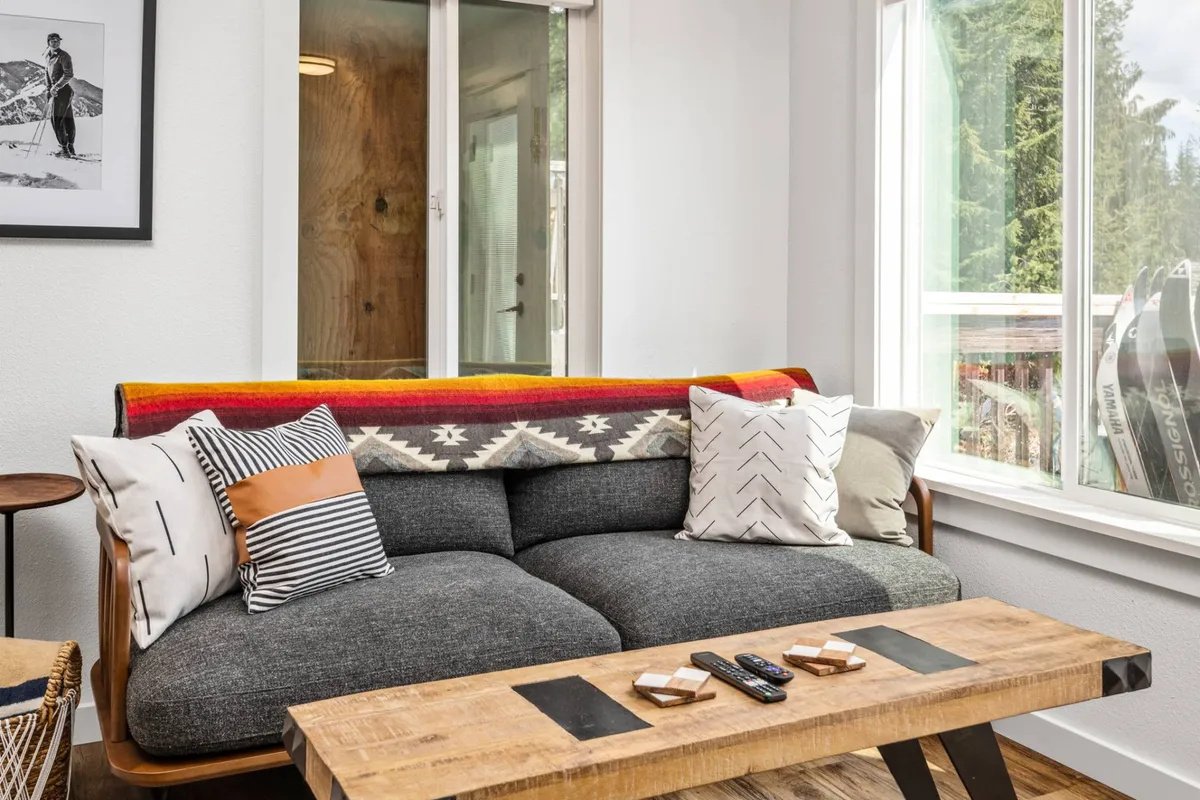 A welcoming living area featuring a comfortable sofa, coffee table, and vibrant wall art. Natural light brightens the space, creating a warm and inviting atmosphere ideal for both relaxation and casual work sessions.