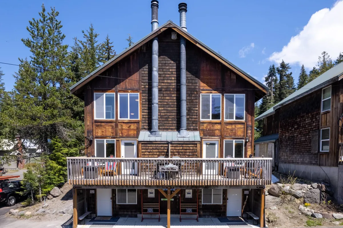 The exterior of the duplex building, featuring a charming wooden facade with a balcony, chimneys, and large windows. The private balcony and inviting exterior are perfect for relaxing or sharing time outside, emphasizing the duplex's structure and privacy.