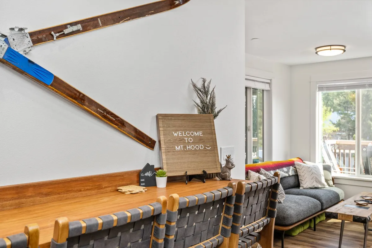 A welcoming entryway decorated with ski-themed accents, a comfortable seating area, a well-lit space with natural light pouring in from the windows, and a visible 'Welcome' sign, evoking the start and end of adventure days.